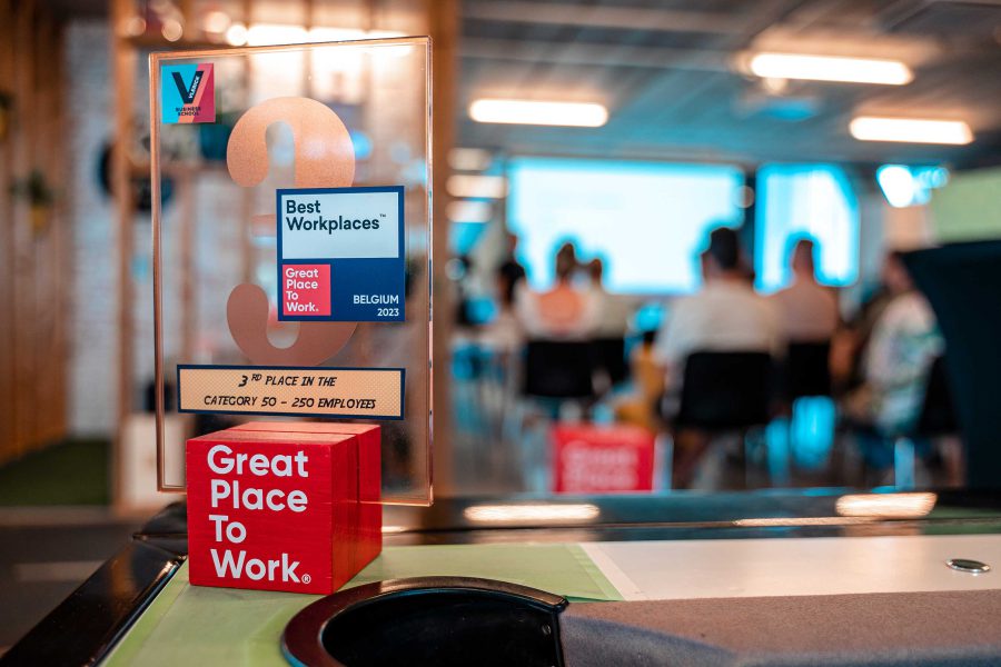 Close up van een Best Workplace trofee met Bewire werknemers in de achtergrond